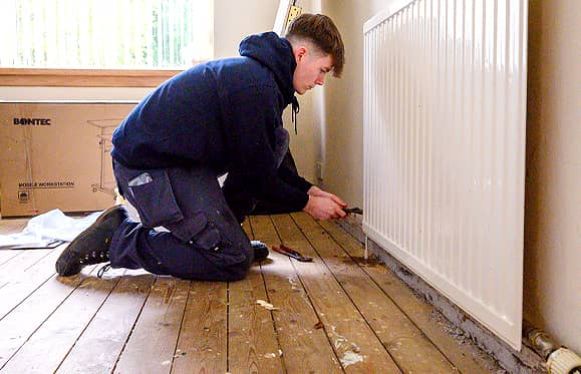 heating engineer fixing radiator